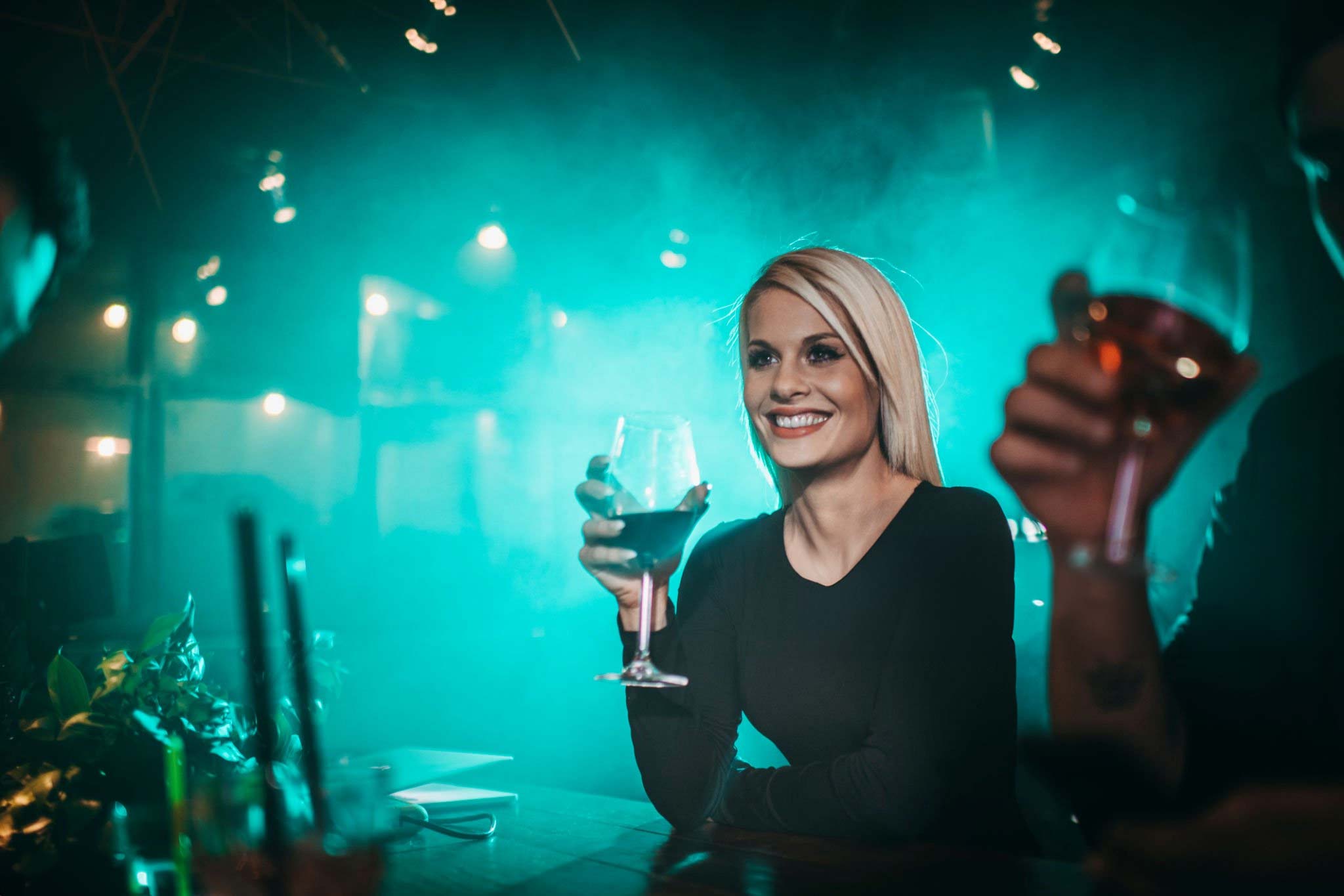 Mujer adulta socializando en un bar nocturno con una copa de vino
