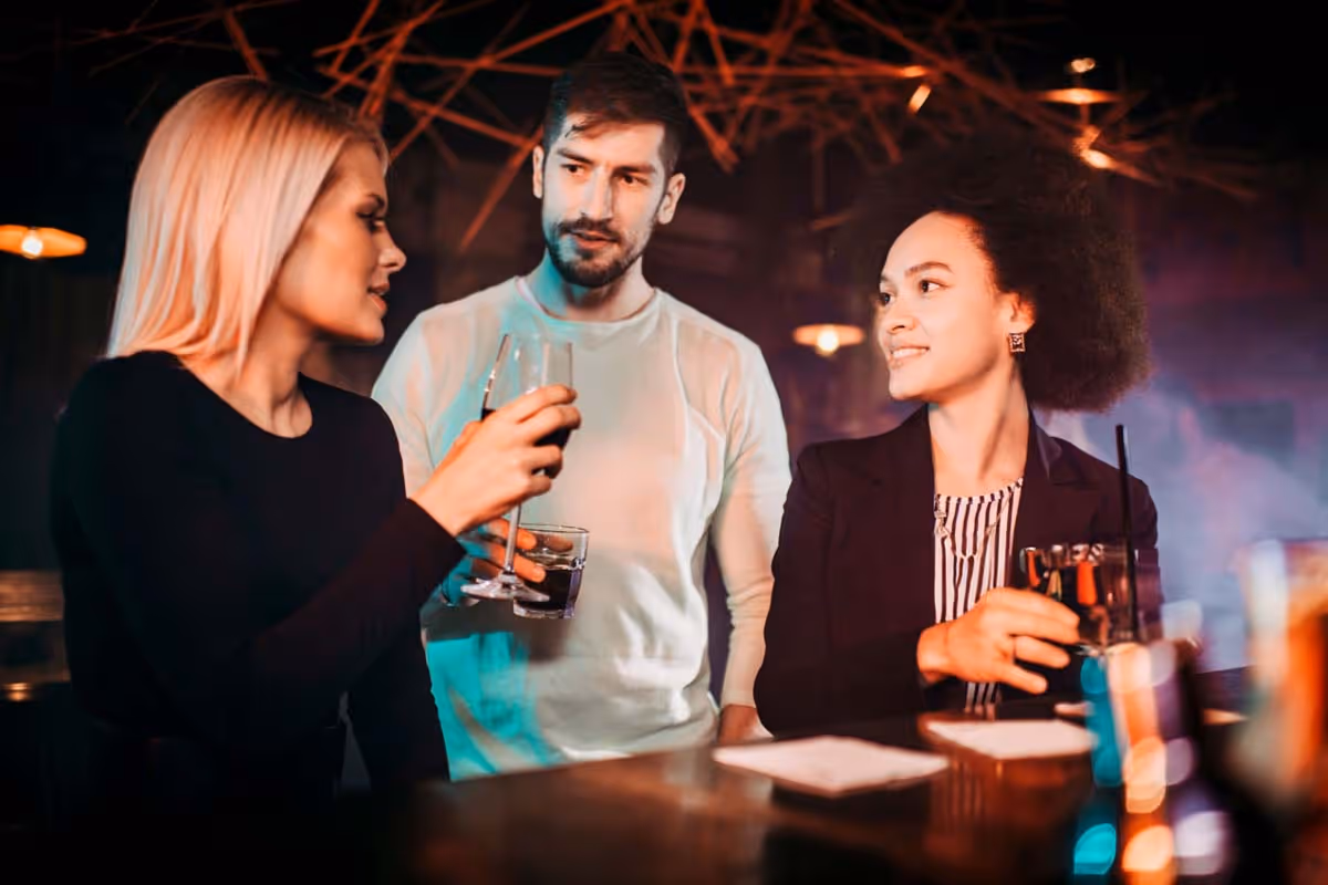ersonas adultas conversando en un bar nocturno durante una salida social